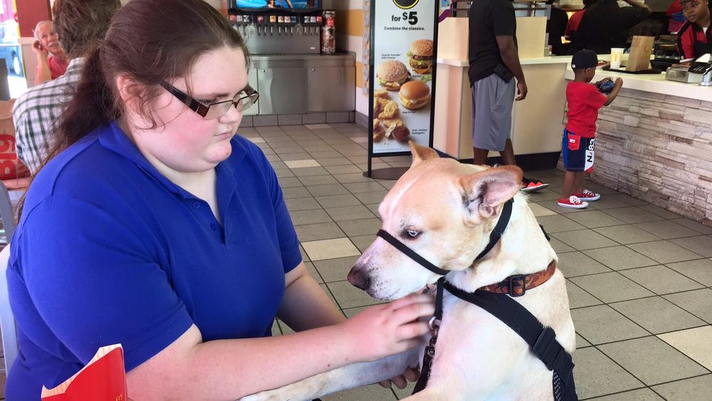 Bonny O'Donnell comforts for service dog, Carson, at a McDonald's in Savannah, GA. O'Donnell relies on Carson to help her handle post-traumatic stress caused by school bullying.