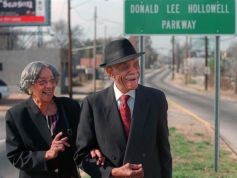 Donald Lee Hollowell (right) stands next to wife Louise Hollowell (left). In the background is a sign that read Donald Lee Hollowell Parkway. 