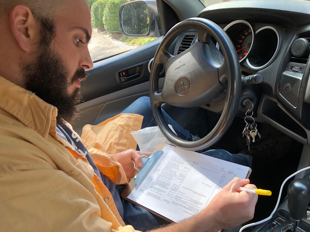 Whit Whitmire of Compostwheels checks a list of homes he has to visit to pick up food waste that will eventually be turned into compost.