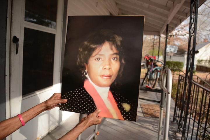 Camille McKnight showing off an old photo of herself from her front porch.