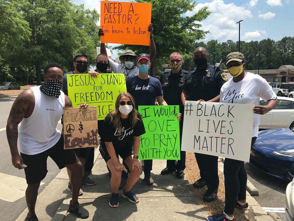 Protesters in pose for a picture with Dunwoody police officers after a protest in front of the police department's headquarters on June 1.