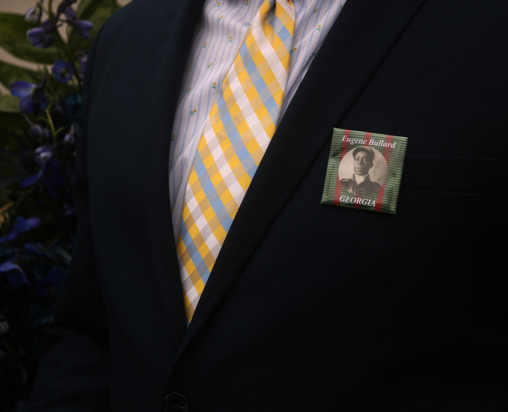 A family member of Eugene J. Bullard's wears a pin with his face on it during the dedication ceremony of the statue honoring Bullard's legacy as the first African American fighter pilot.
