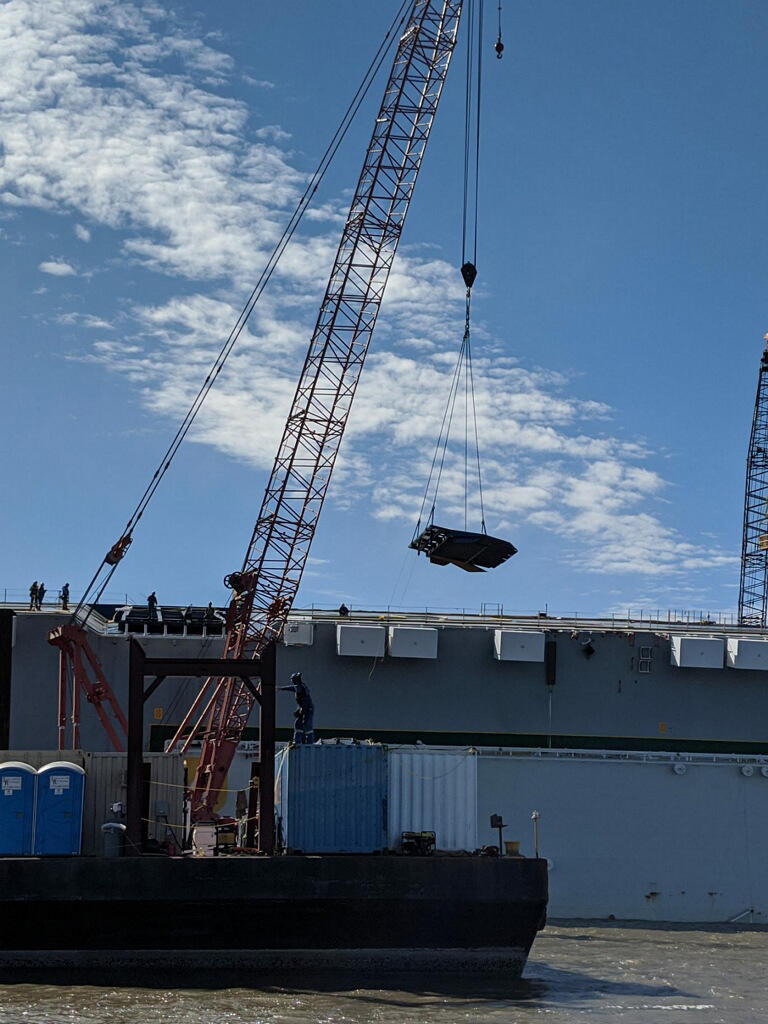 Contractors remove a ramp from the Golden Ray, which is capsized in St. Simon's Sound. The plan to cut up and remove the vessel has been announced.