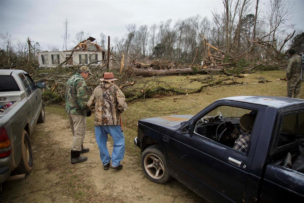 Allen Dwyer, center, makes his way with the help of a neighbor up to what's left of his 160 year old home, destroyed in a tornado Sunday in Talbotton.