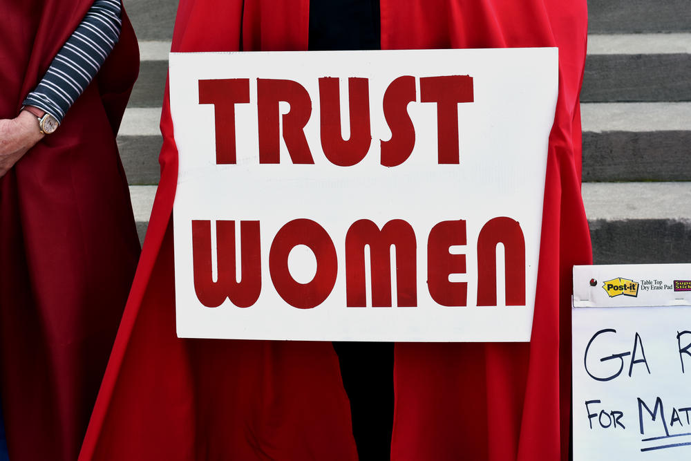 A woman holds a sign reading 'Trust Women' at a protest against Georgia's 