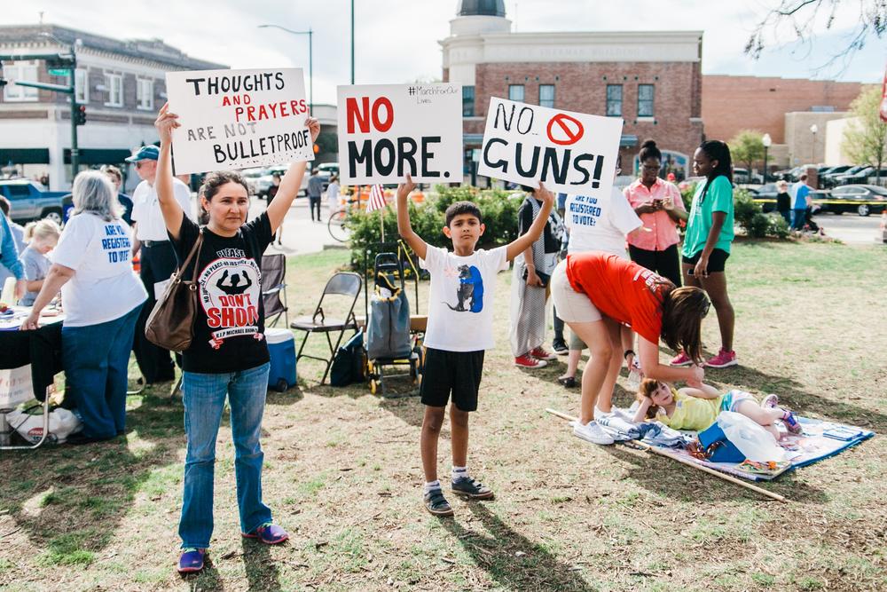 A north Texas mother and her son hold protest signs at the March for Our Lives sister rally in Denton, Texas, on March 24, 2018.