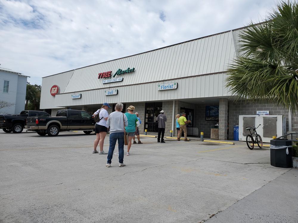 Customers wait to enter Tybee Island's lone, small grocery store, which is allowing only ten shoppers at a time.