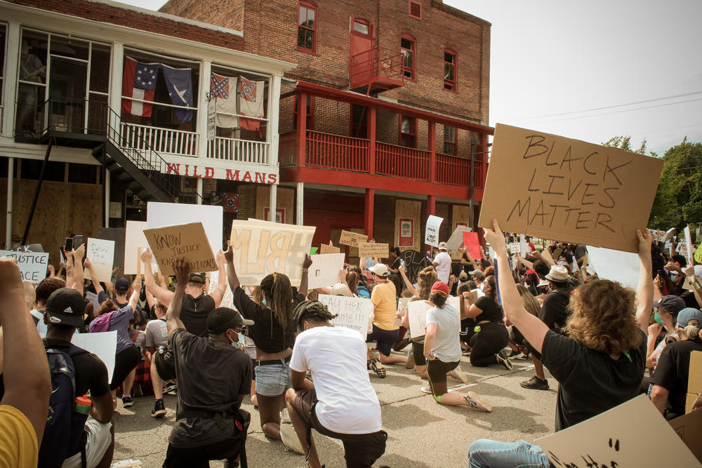 Protesters kneel outside of Wildman's Civil War Surplus in Kennesaw on Sunday.