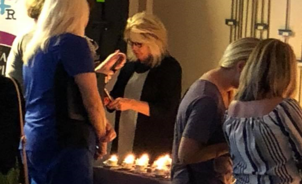 Jennifer Hodge lights candles Tuesday night at the second annual teacup memorial held at the University of North Georgia in Cumming.