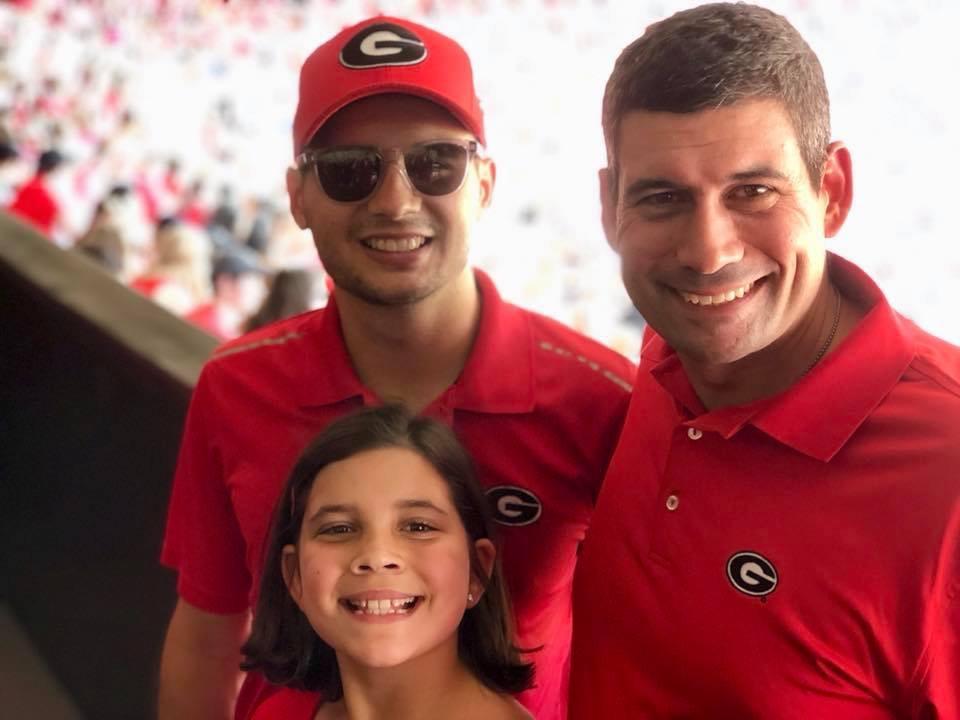 Kyle Chui, a senior at the University of Georgia, enjoys a football game alongside his family. 