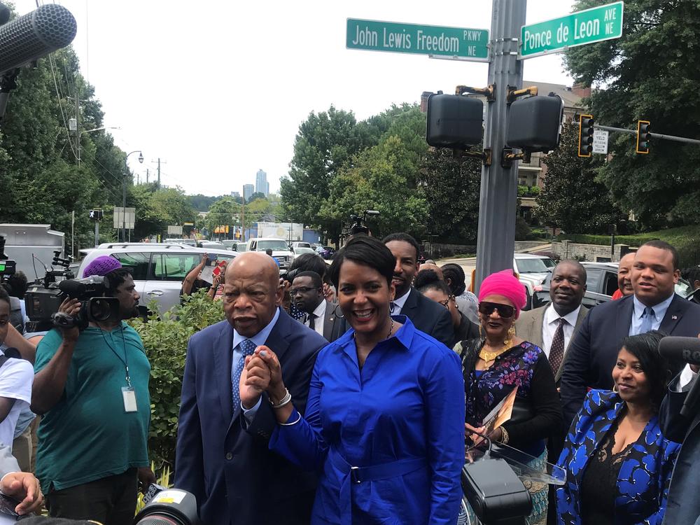 Mayor Keisha Lance Bottoms and Congressman John Lewis join hands undeneath his new street sign.