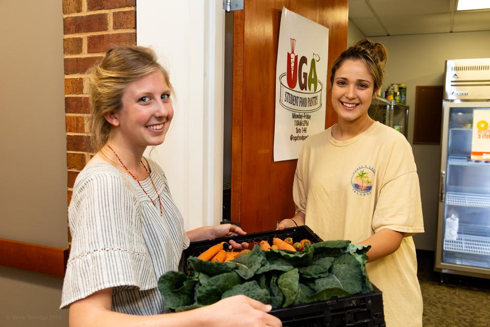 UGArden intern Lily Dabbs, a second-year geography major working toward a certificate in urban and metropolitan studies, delivers the first crop of UGArden vegetables to Ava Parisi.