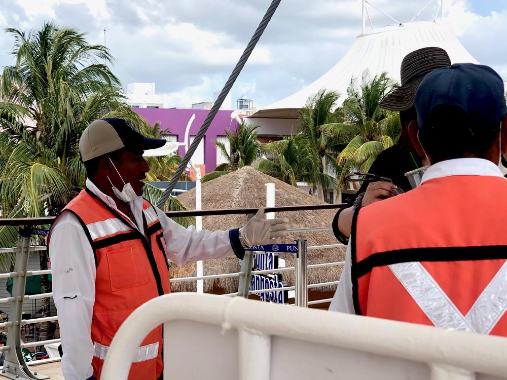 Mexican officials greet travelers trying to reboard their cruise ships in medical masks and gloves in Cozumel, Mexico.