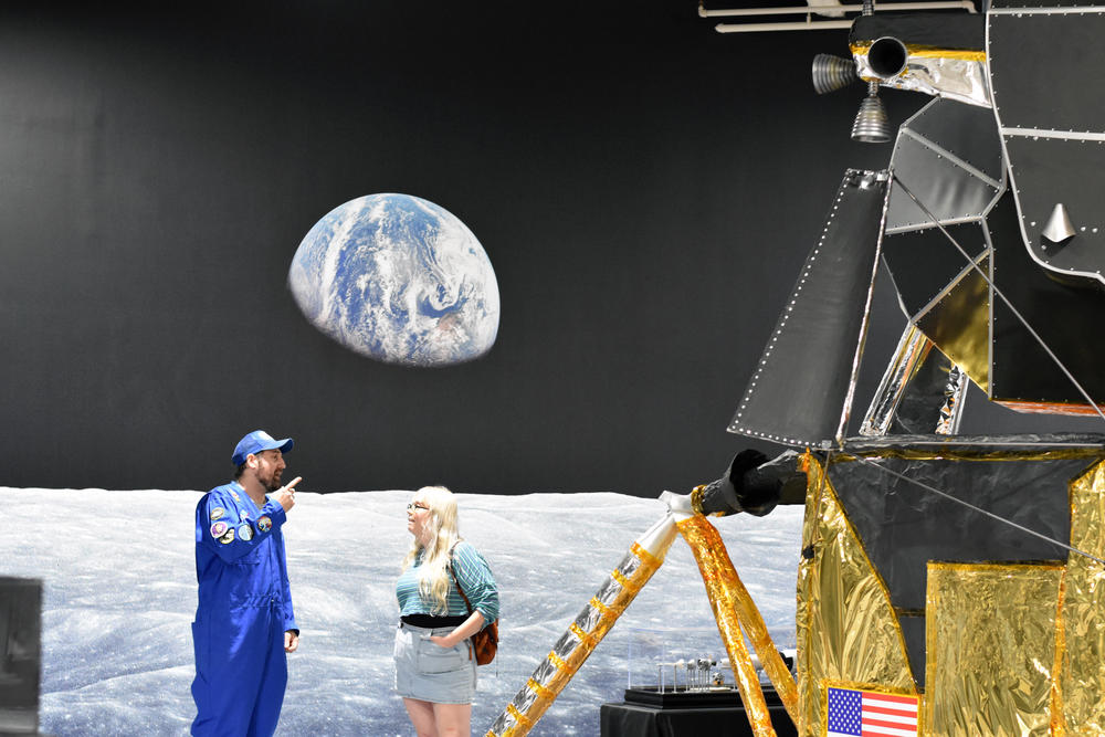 A replica of the Apollo Lunar Module sits in the Computer Museum of America in front of a floor-to-ceiling view of the Earthrise from the moon.