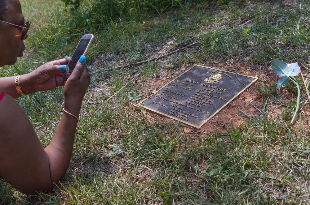 Hope Dorsey makes a photo of a marker commemorating the service during World War Two of her relative George Dorsey. George Dorsey was one of four people killed by a lynch mob at Moore's Ford Bridge in Walton County in 1946.