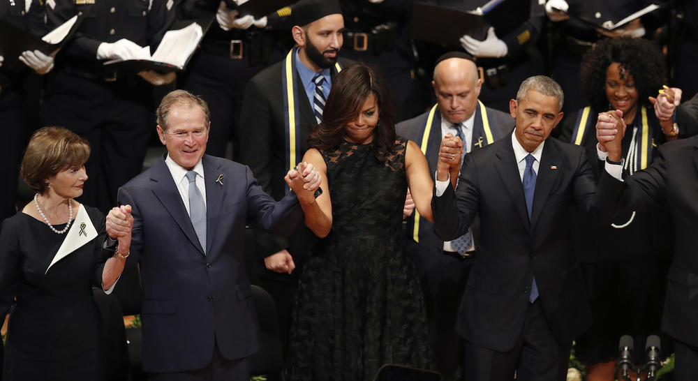 From left, former first lady Laura Bush, former President George W. Bush, first lady Michelle Obama and President Barack Obama join hands during a memorial service with the families of the fallen Dallas police officers.