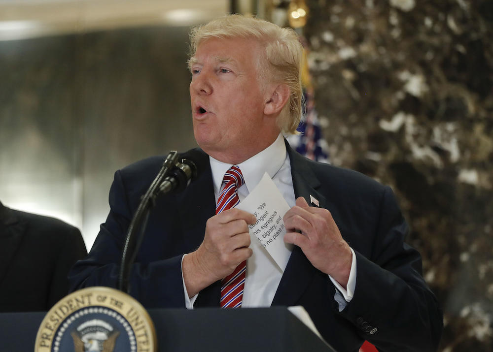 President Donald Trump reaching into his suit jacket to read a quote he made on Saturday regarding the events in Charlottesville, Va., as he speaks to the media in the lobby of Trump Tower, Tuesday, Aug. 15, 2017.