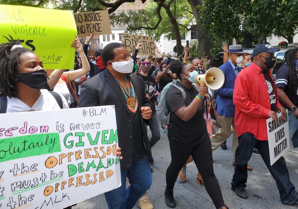 Savannah organizers Faith Harris (left) and Nychorida Austin (with bullhorn) lead a protest march flanked by New Georgia Project chairman Francys Johnson, Savannah Mayor Van Johnson (right, in red) and former Mayor Otis Johnson (right, in blue).