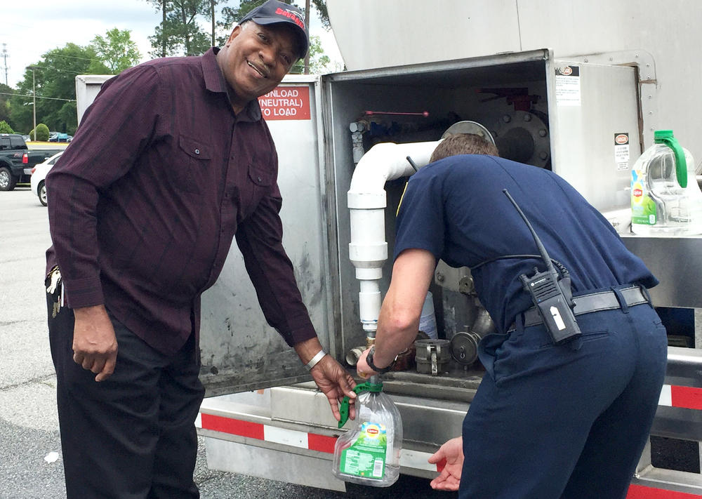 Milledgeville resident James Rayford receives assistance filling plastic containers with sanitized water from Milledgeville Fire Fighter Patrick McCulley. Rayford said he was out getting water for someone who is unable to leave their home.
