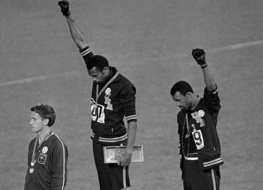 Gold medallist Tommie Smith (center) and bronze medalist John Carlos (right) raise their fists on the podium after the 200 m race at the 1968 Summer Olympics;