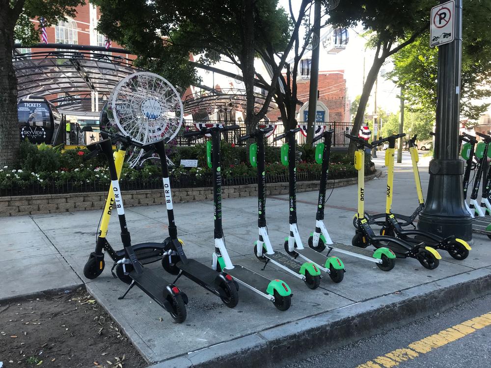 Bolt, Bird, and Lime scooters line the sidewalk in downtown Atlanta.