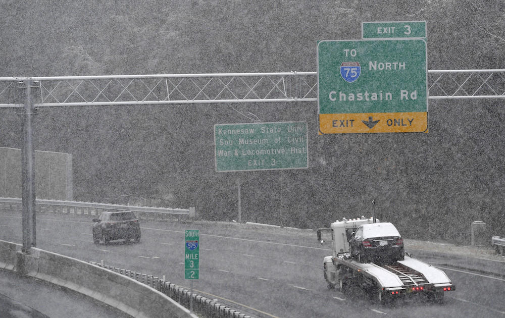 Traffic moves south in a moderate snow, Friday, Dec. 8, 2017, in Kennesaw, Ga. The forecast called for a wintry mix of precipitation across several Deep South states.