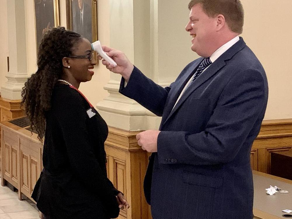 At the Capitol, Rep. Dar'shaun Kendrick has her temperature taken before the start of the special legislative session to approve the governor's declaration of a public health emergency.