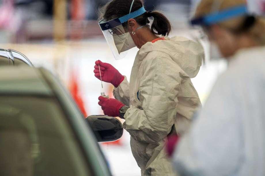 A medical healthcare worker drops a specimen collection into a container after testing a motorist for COVID-19 at a community testing site in the parking lot of La Flor de Jalisco #2 in Gainesville, Ga., Friday, May 15, 2020.