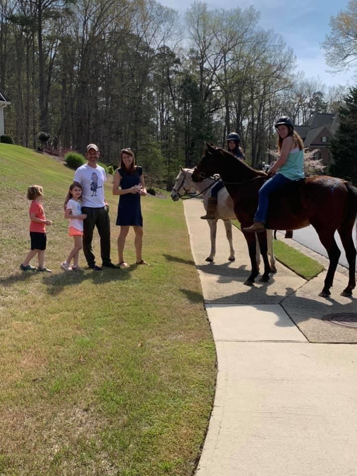 A family full of excitement awaits the arrival of horses in front of their house. 