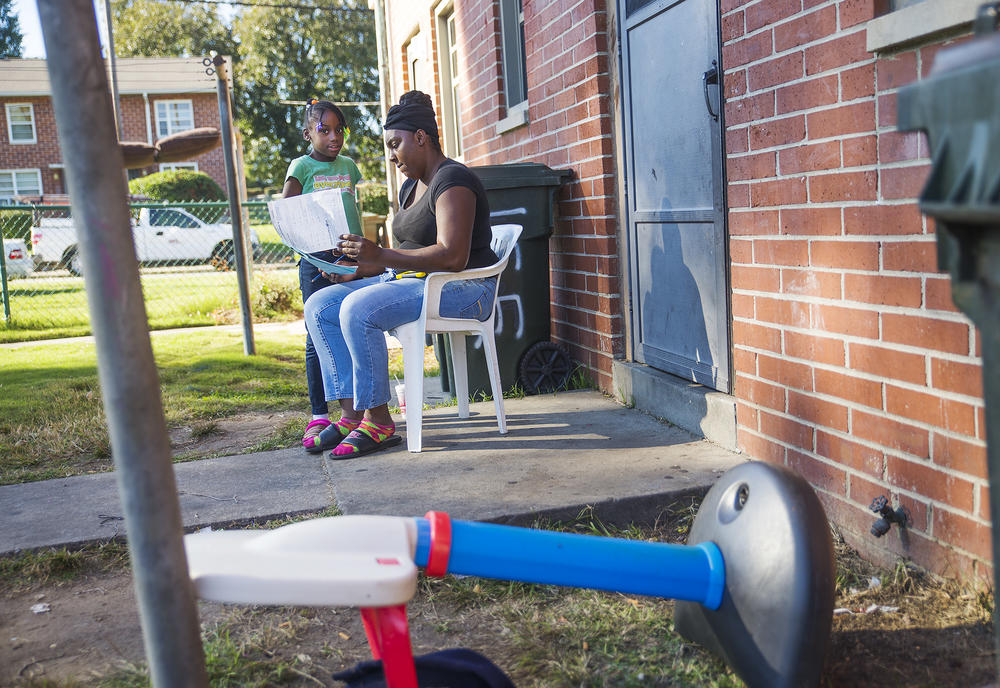 Lashonda Hill helps one of her children with homework outside their apartment in the Tindall Heights Housing Project in Macon. Hill was among a number of women in the neighborhood who hoped that the coming demolition of the projects would mean a shot at m