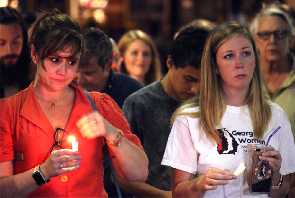 Jenny Wright and Courtney Britt stand for a moment of silent reflection during Lights for Liberty, a candlelit vigil protesting the conditions of migrant detention centers. 