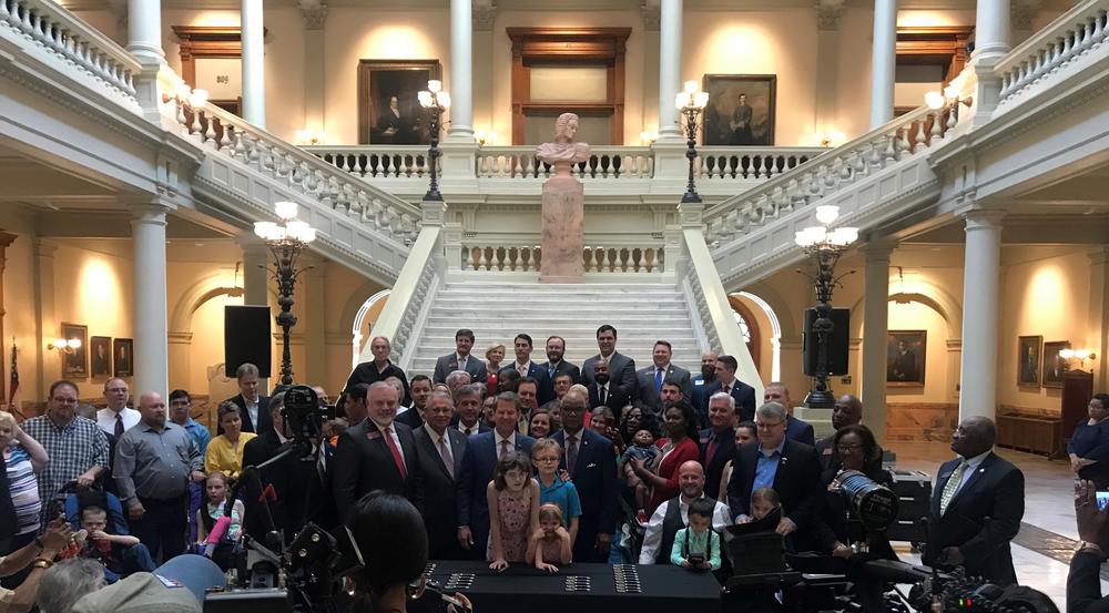 Gov. Brian Kemp, Micah Gravley and other state officials celebrate after the signing of House Bill 324. The bill gives patients more access to medical marijuana. 