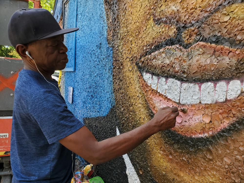 Artist Marvin Weeks paints a mural of Ahmaud Arbery on the side of the future Brunswick African American Cultural Center.