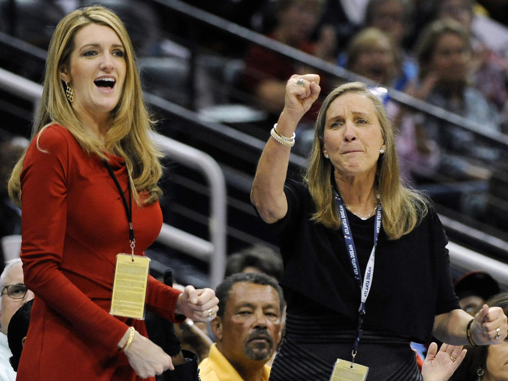 Kelly Loeffler (left), with Mary Brock, cheers the Atlanta Dream on courtside during a 2011 game. Now a senator, Loeffler faces a political challenge over her stake in the WNBA franchise in a tough election race.