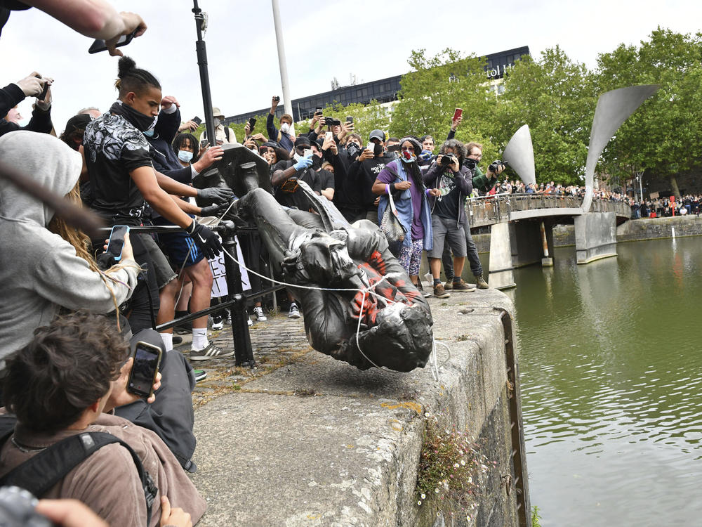 Protesters toss the toppled statue of Edward Colston into the harbor last month in Bristol. The monument to the philanthropist and slave trader had become a flashpoint of protests for racial justice in the U.K.