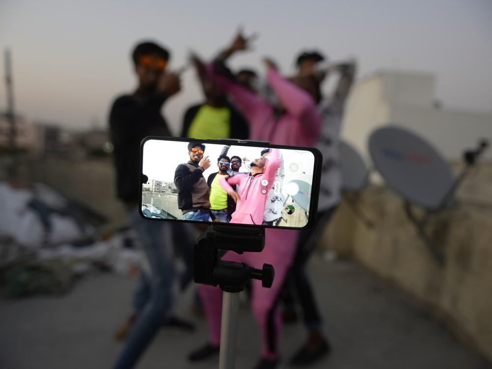 Youths perform in front of a cellphone camera while making a TikTok video on the roof of their residence in Hyderabad, India, in February. India's government has banned 59 Chinese-owned apps including TikTok.