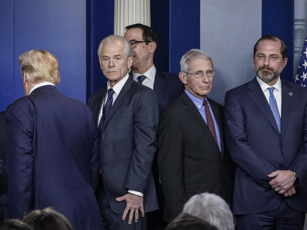 White House economic adviser Peter Navarro (center, left) and Dr. Anthony Fauci, director of the National Institute of Allergy and Infectious Diseases, stand back to back after a White House Coronavirus Task Force briefing on March 9. Navarro wrote an opinion article this week criticizing Fauci.