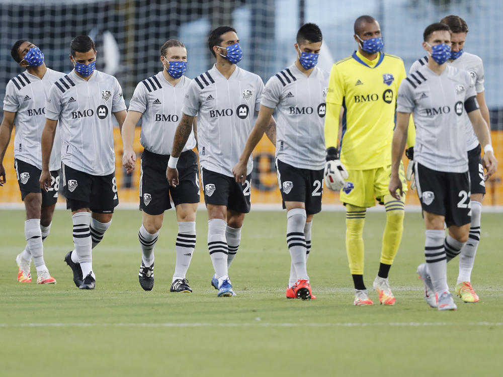 Members of the Montreal Impact, wearing masks, take the field for their match against Toronto FC as part of the MLS Is Back Tournament Thursday in Reunion, Fla.