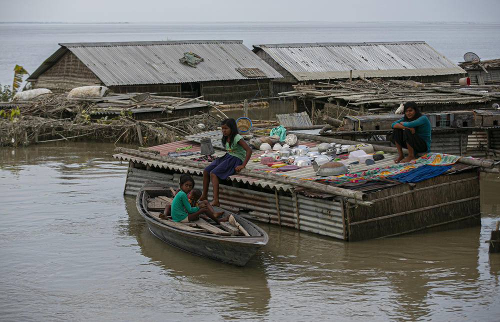 A family takes shelter on the roof of their house submerged in a flood along Brahmaputra river in Morigaon district, Assam, India, Thursday.