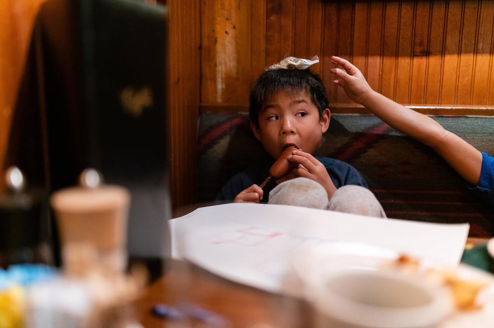 Hayle eats a corndog as Henry stacks oyster crackers on his head at Clyde's Tower Oaks Lodge in Rockville, Md., on Sept. 29, 2019.
