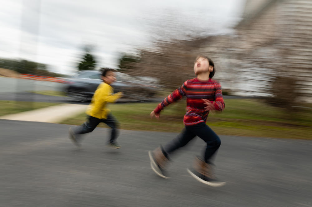 Brothers Hayle (left) and Henry Pham run during a game of football, as their father, Hansel, throws a ball in the air on Jan. 26, 2020.