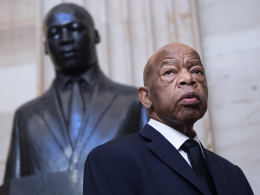 The late Rep. John Lewis, D-Ga., stands near a statue of the Rev. Martin Luther King Jr. in the U.S. Capitol Rotunda in October. Lewis died on Friday at 80.