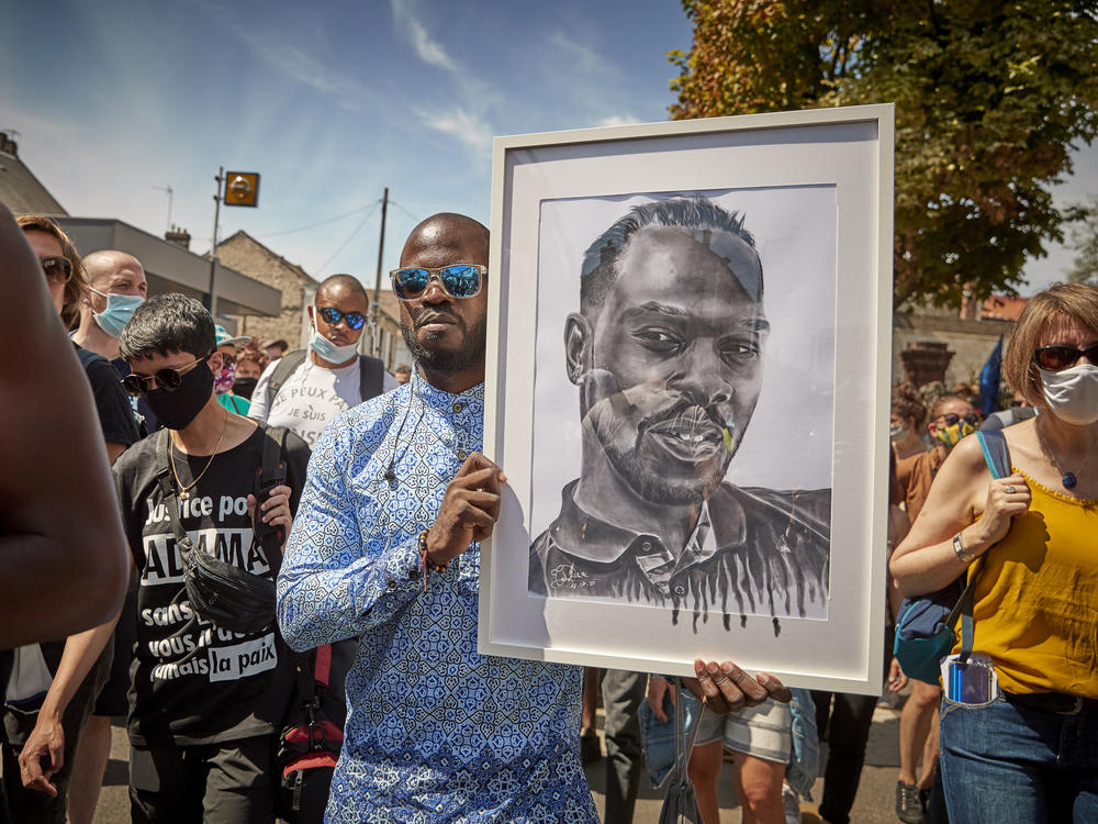A protester holds a portrait of Adama Traoré during demonstrations to commemorate the fourth anniversary of his death, in Persan, France. Last week, judges in charge of investigating Traoré's case announced that various elements of the case would be reexamined.
