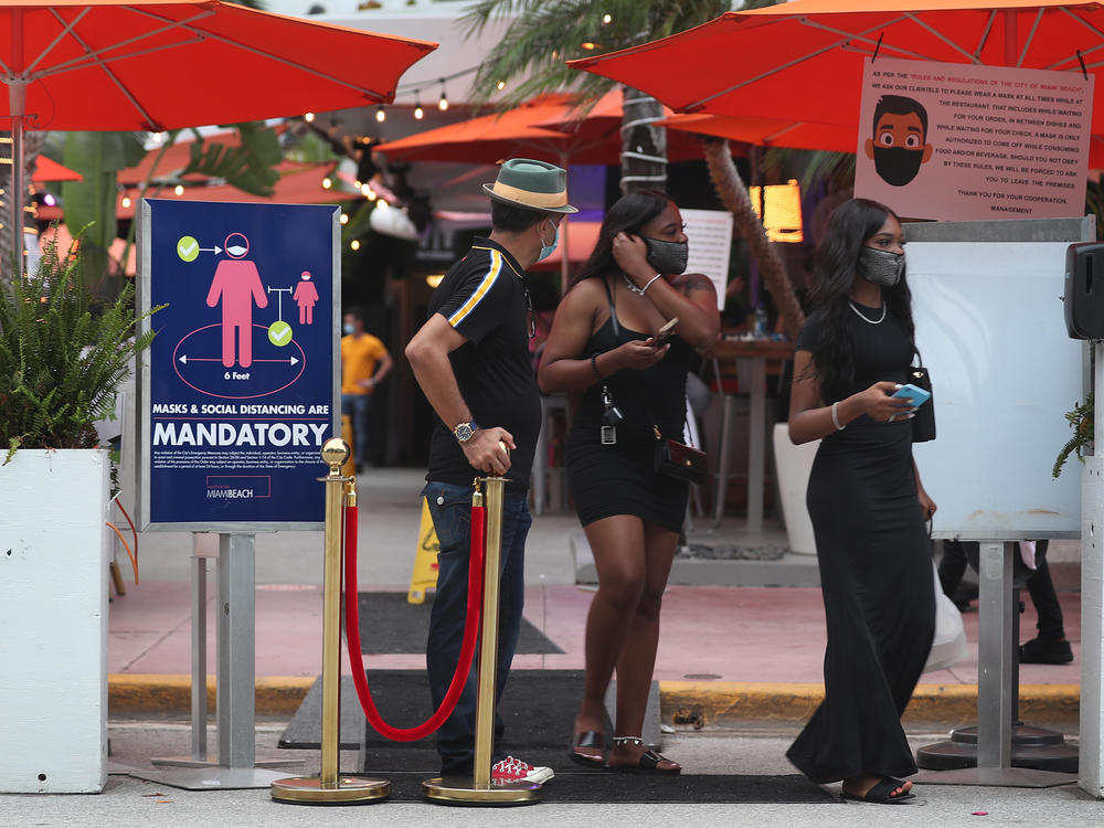People leave the Ocean 10 restaurant as a curfew from 8 p.m. to 6 a.m. is put in place on Saturday in Miami Beach, Fla.