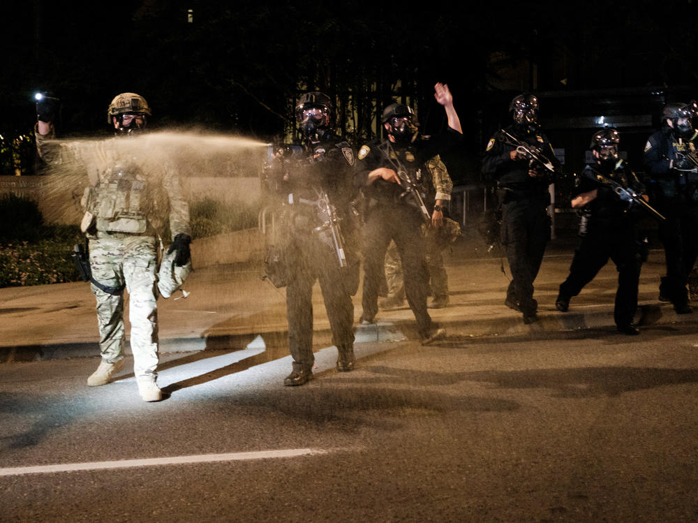 Federal officers use tear gas and other crowd dispersal munitions on protesters Friday outside the Multnomah County Justice Center in Portland, Ore.