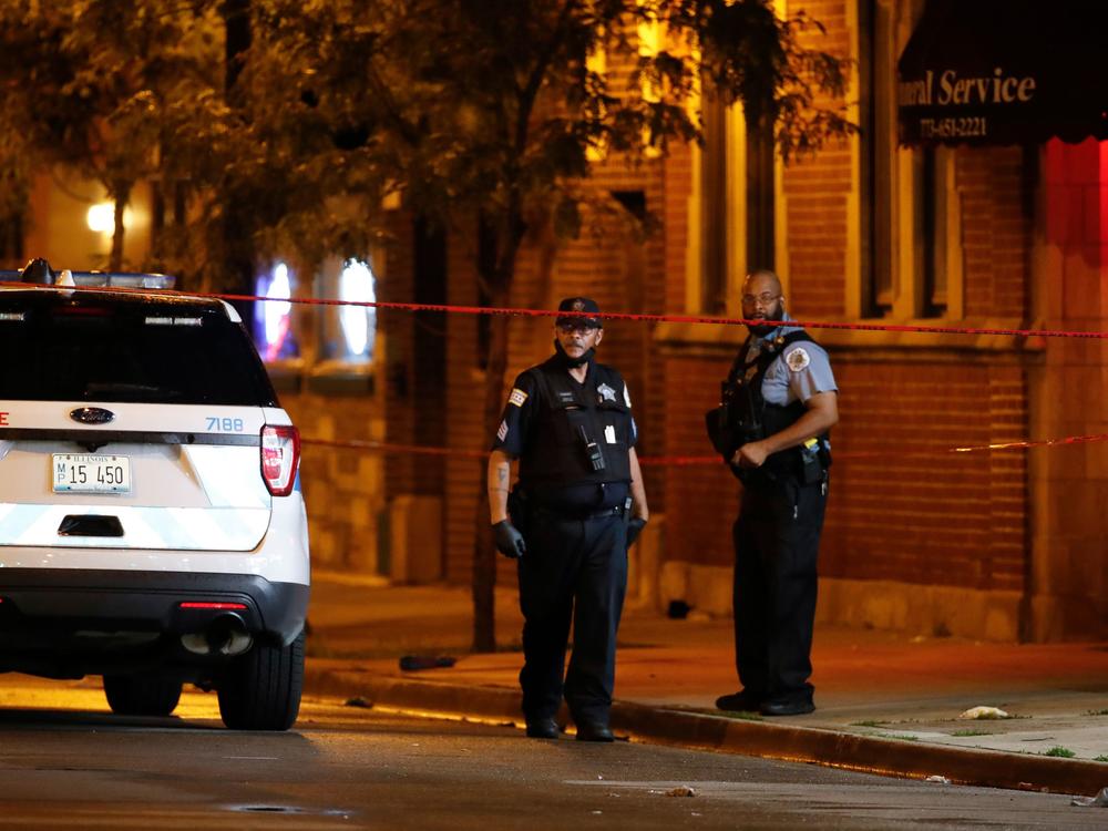 Chicago Police Department officers stand in front of Rhodes Funeral Services as they investigate the scene of a shooting Tuesday night. Gun violence outside a funeral left at least 15 people wounded.
