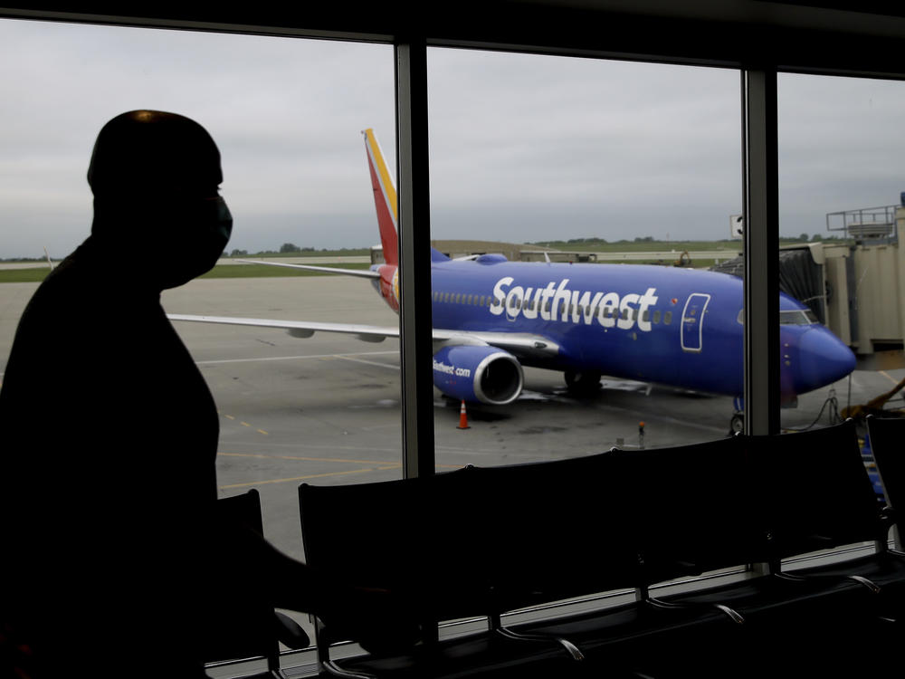 A man wearing a mask prepares to board a Southwest Airlines flight at Kansas City International airport in Kansas City, Mo. Southwest and American Airlines are tightening their mask requirements at the end of July by doing away with exemptions for travelers over the age of 2.