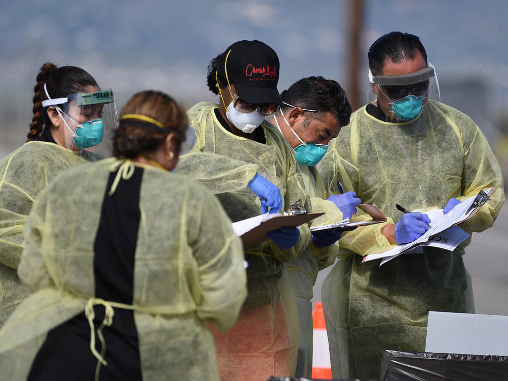 Medical personnel from Riverside University Health Systems hospitals administer a coronavirus test to an individual during drive-through testing in the parking lot of Diamond Stadium on March 22 in Lake Elsinore, Calif.