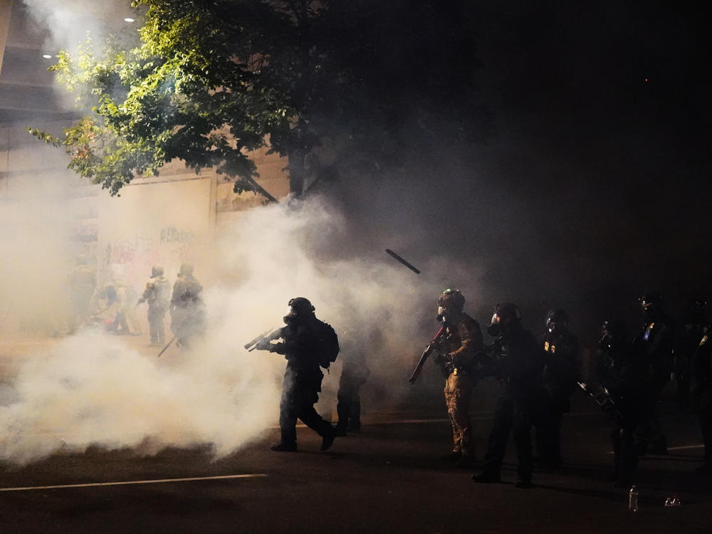 Federal officers walk through tear gas while dispersing a crowd during a July 21 protest in Portland, Ore. A temporary restraining order on Thursday blocked federal agents from knowingly targeting journalists and legal observers.