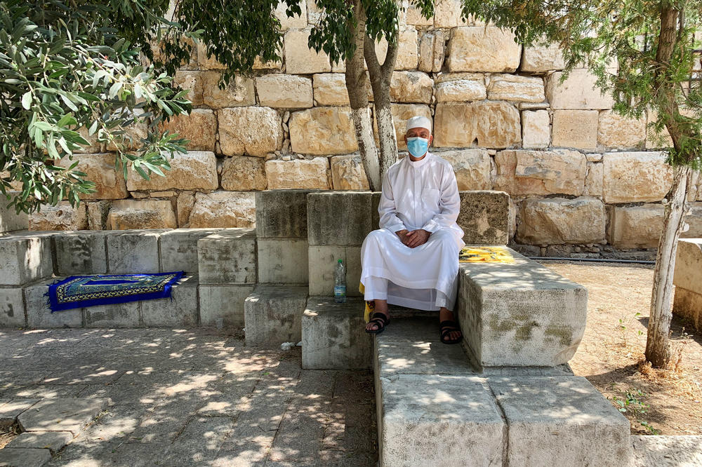 Mustafa Abu Sway, on the Al-Aqsa Mosque advisory council, sits outside the mosque next to his yellow carpet. Worshipers are asked to bring their own prayer carpets from home now. Abu Sway says he's never laundered so many carpets in his life.